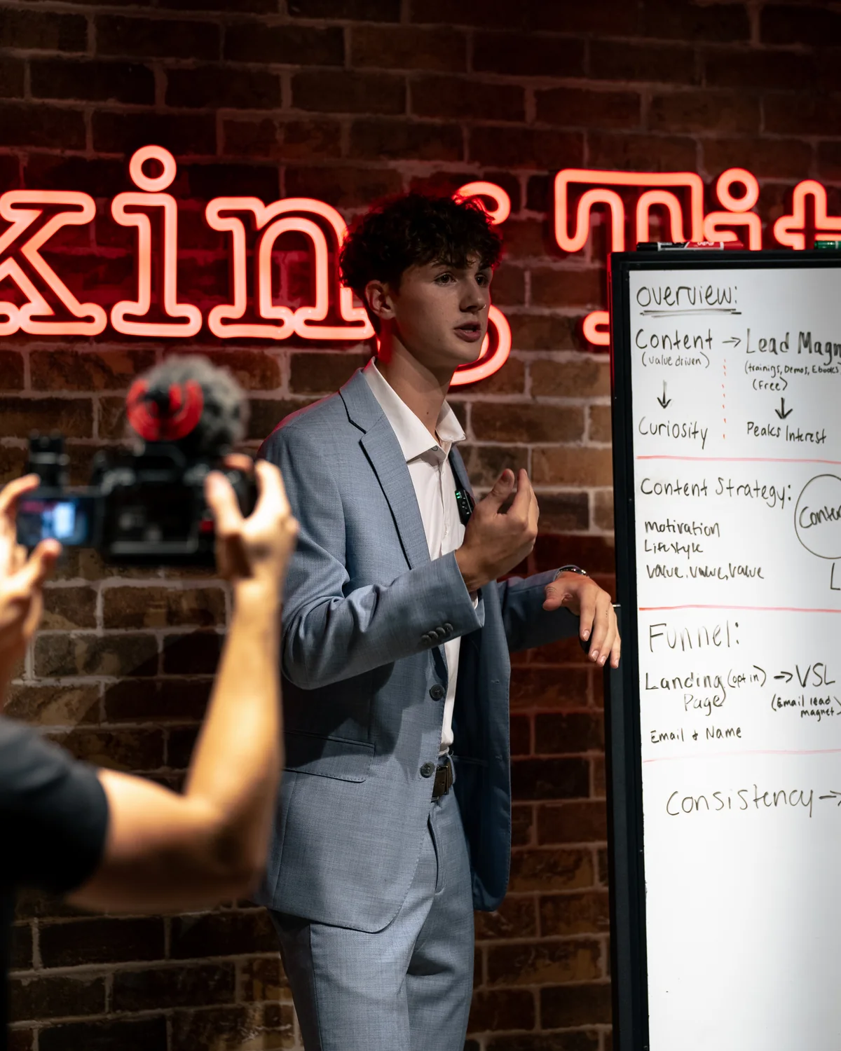 Blake Thomson teaching content strategy at a whiteboard while being filmed